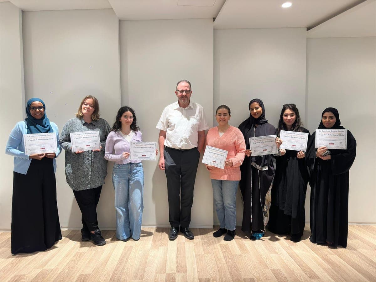 Seven graduates displaying Cognitive Behavioural Skills certificates alongside Dr. John Crimmins