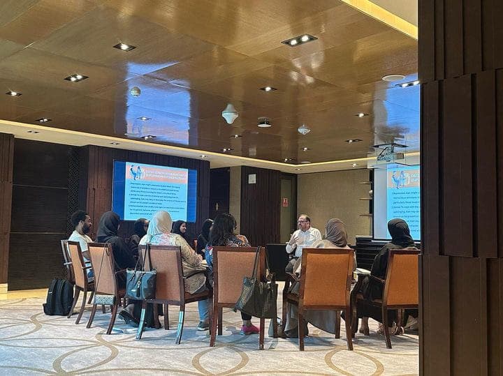 Dr. John Crimmins facilitating an intimate roundtable discussion with slides in a premium conference room